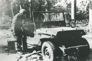 Browse A German soldier inspects a damaged British jeep