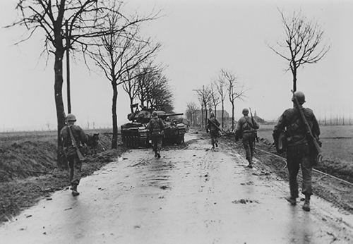 American troops pass a knocked out M24 light tank