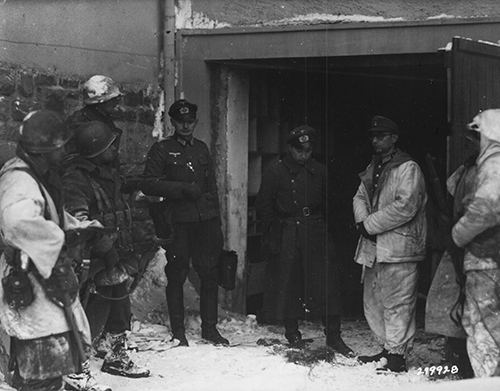 Troops of the 7th Armoured Division guard captured German Officers