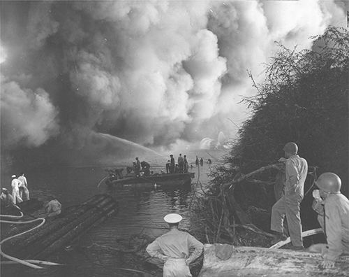 Men watch as fire fighters battle flames in USS LST-480